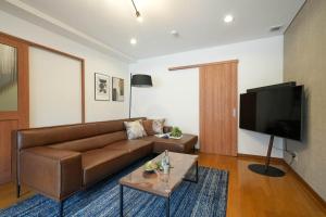 ein Wohnzimmer mit einem braunen Sofa und einem Flachbild-TV in der Unterkunft Canal Villa Otaru - Vacation STAY 99697v in Otaru