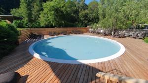 una grande piscina su una terrazza in legno con sedie di Camping Les Vernieres La Bourboule Sancy a La Bourboule