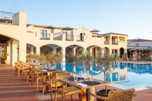 a restaurant with tables and chairs next to a pool at Mangia's Santa Teresa Sardinia, Curio Collection by Hilton in Santa Teresa Gallura