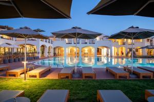 a hotel with a pool with tables and umbrellas at Mangia's Santa Teresa Sardinia, Curio Collection by Hilton in Santa Teresa Gallura