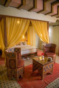 a bedroom with a bed and two chairs and a table at Ksar Elkabbaba Kasbah & SPA in Skoura
