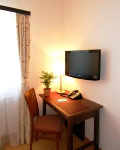 Zimmer mit einem Schreibtisch und einem TV an der Wand in der Unterkunft Hotel Gasthof Der Jägerwirt in Bergheim
