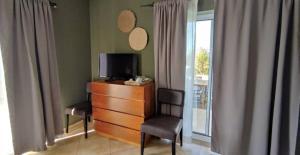 a room with a dresser with a tv and two chairs at Arrifana Destination Suites in Aljezur