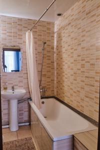 a bathroom with a bath tub and a sink at Hotel Europa in Semey