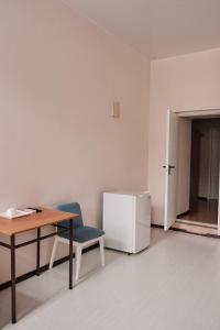 um quarto com uma mesa, uma cadeira e um frigorífico em Hotel Europa em Semey