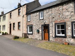an old stone building with a brown door on a street at 2 Bed in Ullswater SZ276 in Stainton