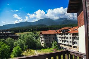 - un balcon avec vue sur les bâtiments et les montagnes dans l'établissement Cozy apartment next to the forest and the gondola, à Bansko