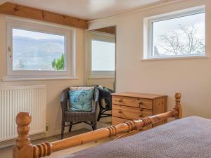 a bedroom with a bed and a chair and windows at 3 Bed in Thornthwaite SZ194 in Braithwaite