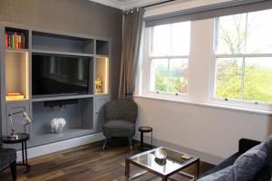 a living room with a couch and a tv and two windows at The West Park Hotel in Harrogate