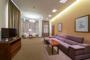 a living room with a couch and a flat screen tv at Alarus Luxe Hotel in Odesa