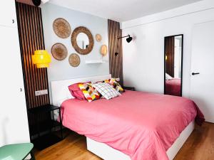 1 dormitorio con cama rosa y espejos en la pared en SG Apartamentos - LA CASA DE SOFÍA VUT-47-14, en Valladolid
