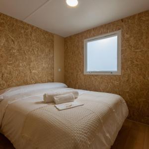a bedroom with a white bed with a window at Camping Costa da Morte in Zas