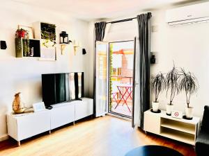 ein Wohnzimmer mit einem TV und einer Tür zu einer Terrasse in der Unterkunft SG Apartamentos - LA CASA DE SOFÍA VUT-47-14 in Valladolid