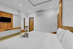 een slaapkamer met een wit bed en een televisie bij OYO Townhouse 801 The Circle in Jaipur