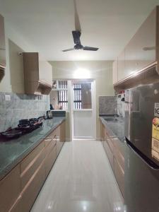 a kitchen with wooden cabinets and a ceiling fan at Symphony Apartments at MIHAN Nagpur in Nagpur