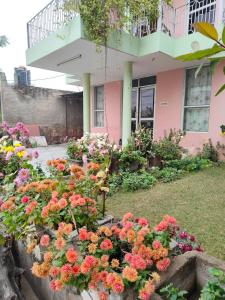 a flower garden in front of a pink house at Hotel Spoonbbill in Bharatpur