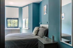 a bedroom with blue walls and a bed with a mirror at OYO Ruby Pub & Hotel in Brighton & Hove