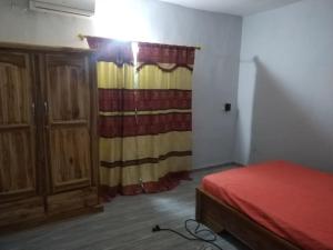 a bedroom with a bed and a dresser and a curtain at villa privée avec garage privé à Lomé Togo 