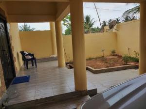 a porch with a black chair and a yellow wall at villa privée avec garage privé à Lomé Togo 