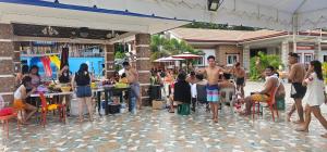un gruppo di persone in piedi e seduti ai tavoli in un patio di PMG Islandscape Resort a Siquijor