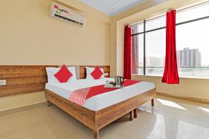 een slaapkamer met een bed met rode gordijnen en een raam bij OYO Star Residency Near Omaxe Gurgaon Mall in Gurgaon