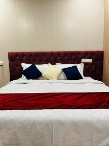 una camera con un grande letto con testiera rossa di The Bluewind Resort a Dehradun