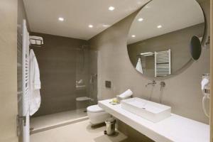 a bathroom with a sink and a toilet and a mirror at Fivos Luxury Suite in Athens