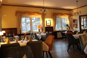 a dining room with tables and chairs and windows at Landhaus Silberberg in Winterberg