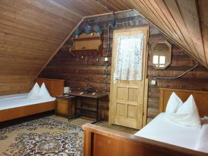 an attic room with two beds and a door at Casa Lacramioara in Sîmbăta de Sus