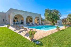 a backyard with a pool and chairs and a house at Tenuta Palù By Raro Villas in Carovigno