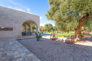 a patio with chairs and a tree and a pool at Tenuta Palù By Raro Villas in Carovigno
