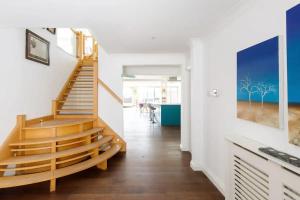 una escalera en una casa con paredes blancas y suelo de madera en The Kite House en East Wittering