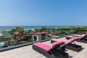 a row of lounge chairs on a roof with the beach at The Kite House in East Wittering