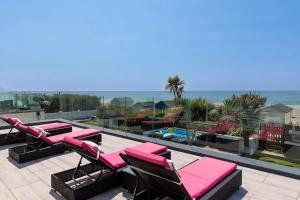 a patio with pink lounge chairs and the ocean at The Kite House in East Wittering