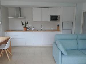 ein Wohnzimmer mit einem blauen Sofa und einer Küche in der Unterkunft Apto a 1 minuto de la Playa en Sant Antoni in Sant Antoni de Calonge