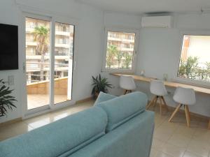 ein Wohnzimmer mit einem blauen Sofa und Fenstern in der Unterkunft Apto a 1 minuto de la Playa en Sant Antoni in Sant Antoni de Calonge