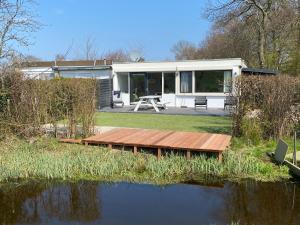 a house with a wooden bridge over a body of water at Place 2 Beach Next to Ijsselmeer in Lemmer
