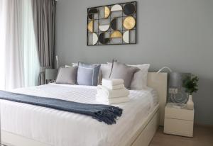 1 dormitorio con cama blanca y almohadas azules en Cassia Residences by NLA en Bang Tao Beach