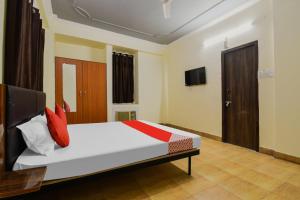 una camera da letto con un letto con cuscini rossi e una TV di Super OYO Olive Grand a Patna