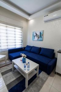 a living room with a blue couch and a table at Amman Sun Apartments in Ţāb Kirā‘