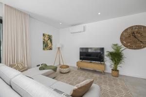 ein Wohnzimmer mit einer weißen Couch und einer Uhr in der Unterkunft Terraços de Quarteira II Frolic by Real Properties in Cavacos