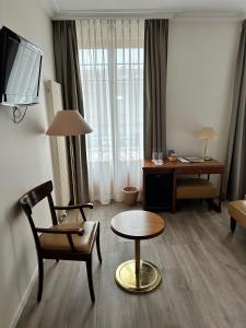 ein Wohnzimmer mit einem Stuhl, einem Tisch und einem Schreibtisch in der Unterkunft Hôtel des Alpes in Nyon