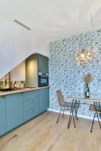 een keuken met blauwe kasten en een tafel en stoelen bij Les Voiles - Appart'hotel "Le Nordet" in Carnac