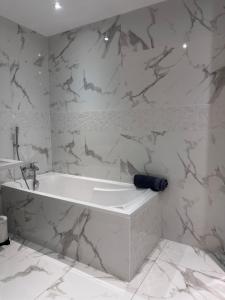 y baño con bañera blanca y paredes de mármol. en Chez Mathieu, en Saint-Dizier