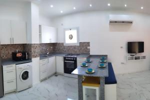 Condo with Breathtaking 's view with 2 bedrooms في الغردقة: مطبخ به دواليب بيضاء وطاولة عليها صحون زرقاء