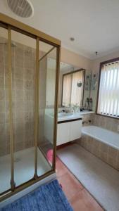 Q’s Home Stay في Claremont: حمام مع دش وحوض استحمام ومغسلة