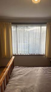 Q’s Home Stay في Claremont: غرفة نوم بسرير ونافذة كبيرة