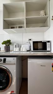cocina con lavadora y microondas en Q’s Home Stay, en Claremont