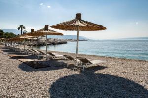 a group of chairs and umbrellas on a beach at Apartment Radosevac Beach in Split