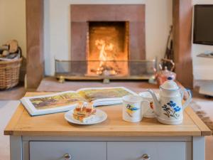 a table with two cups and a book and a fireplace at 3 Bed in Lazonby SZ198 in Kirkoswald